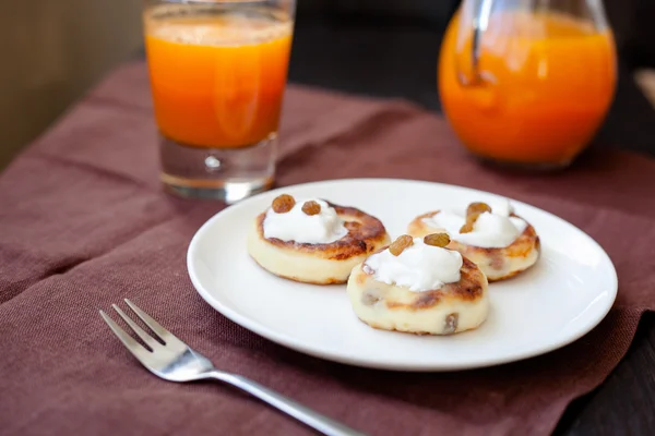 Heerlijke huisgemaakte kaas pannenkoeken met verse wortelsap — Stockfoto