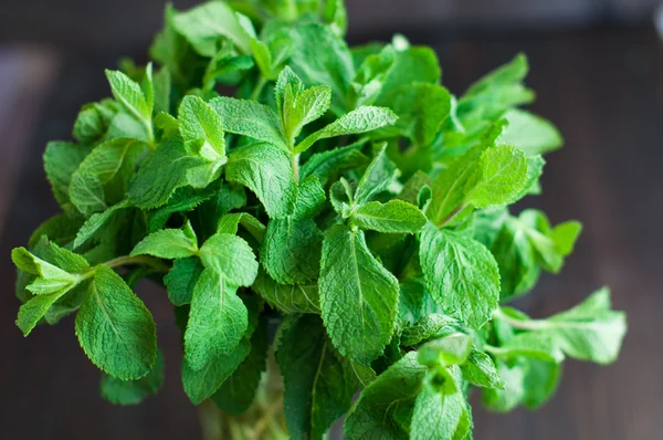 Foglie di menta fresca su uno sfondo di legno — Foto Stock