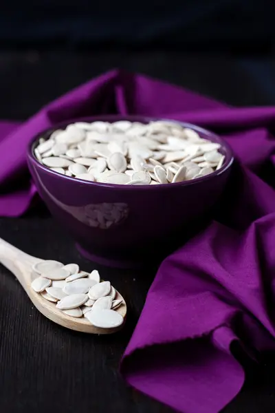 A bowl with toasted pumpkin seeds and wooden spoon — Stock Photo, Image