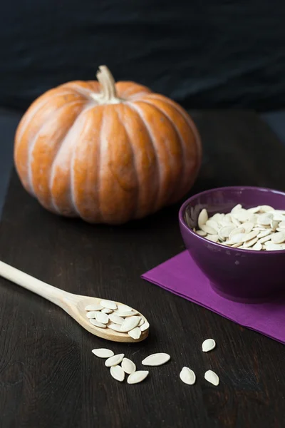 Bowl with toasted pumpkin seeds and wooden spoon — Stock Photo, Image