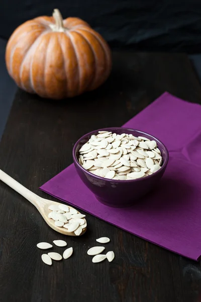 Bowl with toasted pumpkin seeds and wooden spoon — Stock Photo, Image