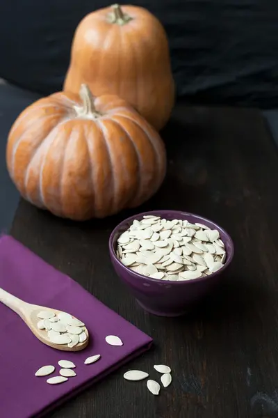 Bowl with toasted pumpkin seeds and wooden spoon — Stock Photo, Image