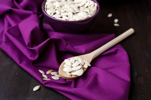 A bowl with toasted pumpkin seeds and wooden spoon — Stock Photo, Image