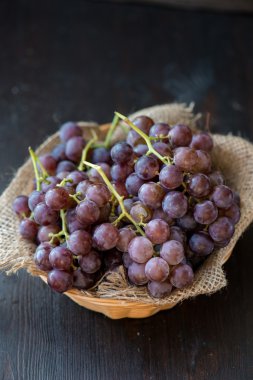 Ahşap masa üzerinde sepet üzüm demet