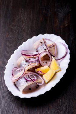 Biber, otlar, tuz ve limon üzerinde beyaz seramik plat ile ringa balığı