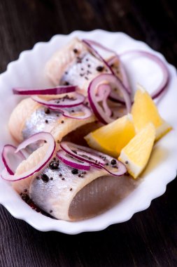 Biber, otlar, tuz ve limon üzerinde beyaz seramik plat ile ringa balığı