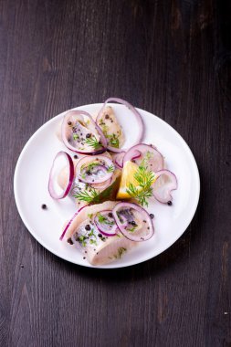 Biber, otlar, tuz ve limon üzerinde beyaz seramik plat ile ringa balığı