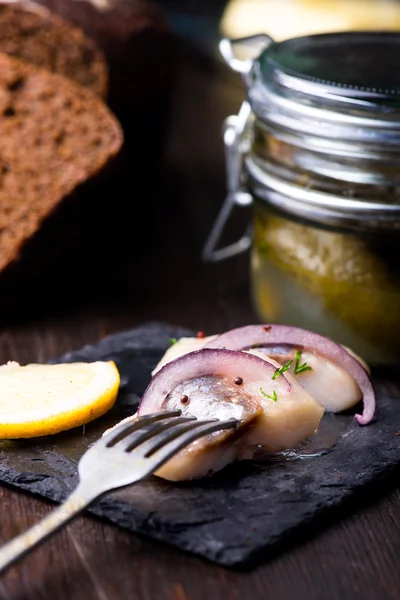 Arenque con limón en un plato negro de pizarra — Foto de Stock