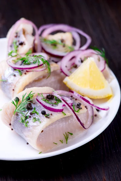 Aringa con pepe, erbe aromatiche, sale e limone su un piatto di ceramica bianca — Foto Stock