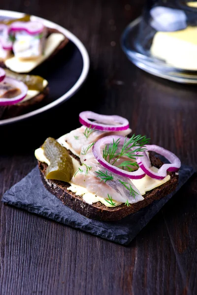 Herring sandwich on a black slate plate — Stock Photo, Image