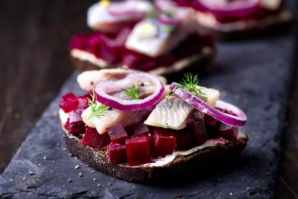 Sandwiches con arenque y remolacha en un plato de pizarra — Foto de Stock