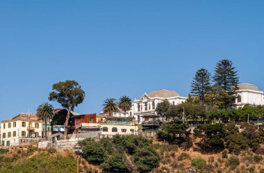 Valparaiso, Şili - 8 Aralık 2008: Mavi gökyüzü altındaki kıyı şeridi üzerindeki yeşil tepenin üzerindeki tarihi binalar ve Art Cafe Mirador.