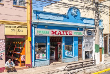 Valparaiso, Şili - 8 Aralık 2008: Küçük perakende mağazaları, 1 pastane ve 1 bakkal, sokak boyunca canlı renklerle boyanmış ve girişte oturan 1 tüccar. 