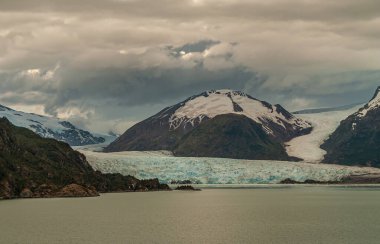 Sarmiento Kanalı, Şili - 11 Aralık 2008: Amalia Buzulu fiyort suyunda eriyor. Mavimsi renk ve yeşilimsi su. Yukarıdaki kalın gri bulut.