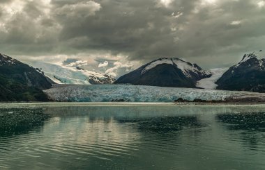 Sarmiento Kanalı, Şili - 11 Aralık 2008: Amalia Buzulu. Mavimsi erime noktalarının manzarası ve kahverengi yağmurlu bulutların altındaki kayalık dağlarda buzul akıntılarını gösteriyor..