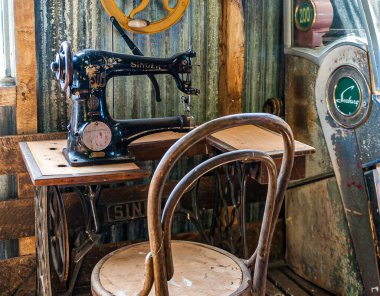 Riesco Adası, Şili - 12 Aralık 2008: Posada Estancia Rio Verde çalışma çiftliği. Eski siyah şarkıcı dikiş makinesi ahşap masa üzerinde ve barakada bir sandalye..