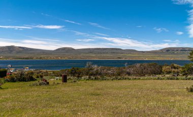 Riesco Adası, Şili - 12 Aralık 2008: Posada Estancia Rio Verde çalışma çiftliği. Otwau Boğazı 'nın önündeki yeşil çiftlik arazisi ve mavi bulutların altındaki dağ sırası..
