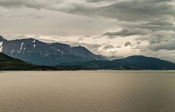 Tierra Del Fuego アルゼンチン 2008年12月13日 西側ビーグル海峡 灰色の光を反射する水の後ろの雪の山の範囲の上に軽い雲の風景 海岸線の森 — ストック写真