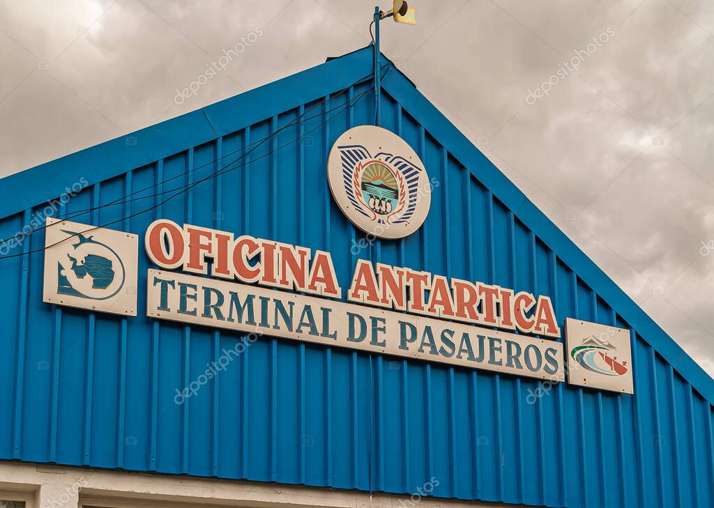 Ushuaia, Tierra del Fuego, Argentina - December 13, 2008: Red-blue-white letters on sign on blue facade of passenger terminal for Antartica travelers under brown sky.