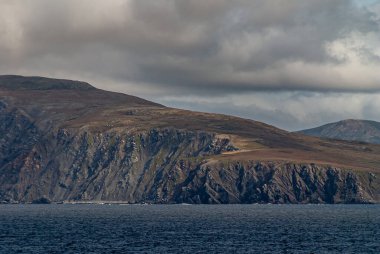 Horn Burnu, Wollaston Adaları, Şili - 14 Aralık 2008: Kahverengimsi bulutların altındaki mavi okyanusun arkasındaki ada kayalıklarının kapatılması.