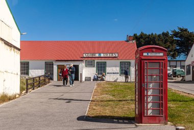 Stanley, Falkland Adaları, İngiltere - 15 Aralık 2008: Globe Tavern, tam mavi gökyüzünün altında kırmızı çatılı, önünde klasik İngiliz telefon kulübesi olan beyaz bir bina. Mevcut insanlar.