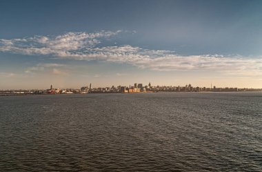 Montevideo, Uruguay- 18 Aralık 2008 Rambla Bulvarı boyunca açık mavi sabah bulutları altında Rio de la Plata 'nın karanlık sularından görülen geniş şehir manzarası başlıyor..