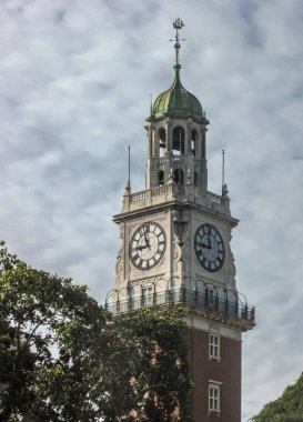 Buenos Aires, Arjantin - 19 Aralık 2008 İngiliz deniz saat kulesinin üst bölümü yeşil yapraklı mavi bulutlu manzaraya karşı. 