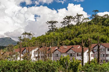 Petropolis, Brezilya - 23 Aralık 2008: Önü ve üstü yeşil yapraklarla çevrili mavi bulutlu kırmızı çatıları olan yeni beyaz konut kompleksi.