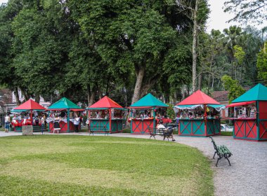 Petropolis, Brezilya - 23 Aralık 2008: Yeşil Park 'ta Noel: Yeşil ağaçların önünde satıcılar ve müşterilerle birlikte yeşil-kırmızı pazar kabinleri sırası.