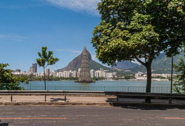 Rio de Janeiro, Brezilya - 23 Aralık 2008: Lagoa Rodrigo de Freitas 'taki sahte Noel ağacı Redeemer heykeli mavi gökyüzünün altındaki dağın tepesinde. Apartman kemeri.