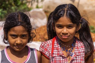 Kadenahalli, Karnataka, Hindistan - 3 Kasım 2013: Siyah saçlı ve renkli elbiseli iki genç çiftlik kızının yüzlerinin yakın çekimi.