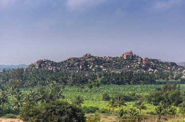 Hampi, Karnataka, Hindistan - 4 Kasım 2013: Sunset Hill namı diğer Hemakatu. Yeşil tarım arazisinin geniş yeşil manzarası. Ufukta bir sürü ağaç ve kayalık tepe var. Açık mavi gökyüzünün altında..