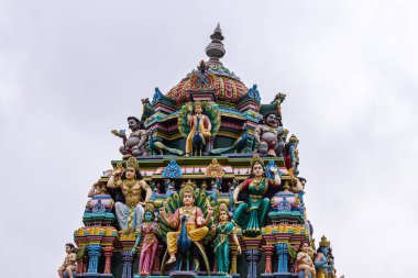 Kadirampura, Karnataka, Hindistan - 4 Kasım 2013: Sri Murugan Tapınağı. Gümüş bulutlara karşı Gopuram 'ın tepesindeki renkli heykeller. Tavus kuşu üzerinde iki kez Murugan. En dipte bu iki eş..