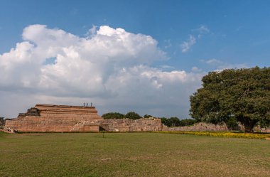 Hampi, Karnataka, Hindistan - 4 Kasım 2013: Mahanavami Dibba veya Dussehra Platformu. Mavi bulutların altında kahverengi taşlar. Önünde yeşil ot olan daha geniş bir alan. Tarihe geçen duvar.
