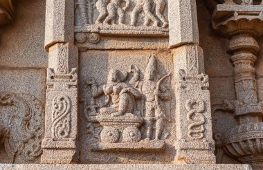 Hampi, Karnataka, Hindistan - 4 Kasım 2013: Hazara Rama Tapınağı. Duvardaki bej rengi taş heykelin yakın çekimi. Yayı taşıyan kadın ve erkek el arabasında. Yılan resimleri.