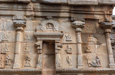 Hampi, Karnataka, Hindistan - 5 Kasım 2013: Sri Krishna tapınağı yıkıldı. Kahverengi-bej taşlı ön cephede fresk olarak çeşitli pozisyonlardaki insanların heykelleri var. Oyulmuş sütunlar ve boş oyuklar..