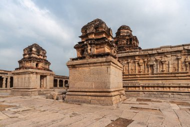 Hampi, Karnataka, Hindistan - 5 Kasım 2013: Sri Krishna tapınağı yıkıldı. Ana tapınak binasının önündeki 2 kahverengi küçük tapınak, hepsi açık mavi bulutların altında koyu kahverengi vimanalar..