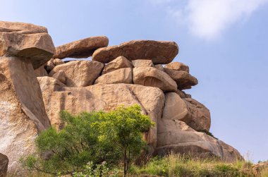 Hampi, Karnataka, Hindistan - 5 Kasım 2013: Kardeş Taşlar grubu. Düz olanlar mavi bulutların altında, yeşil yapraklar önde..