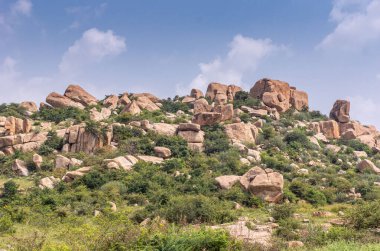 Hampi, Karnataka, Hindistan - 5 Kasım 2013: KudureGombe mandapam ve antik kuyu. Etrafı, mavi bulutların altındaki yeşil çalı kaplı tepelerde dağılmış kahverengi kayalarla çevrili..