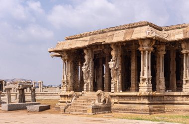 Hampi, Karnataka, Hindistan - 5 Kasım 2013: Vijaya Vitthala Tapınağı. Bej şekilli sütunlarla giriş ve açık mavi bulutlar altında bir sığınağın mandapam 'ına giden adımlar. At ve fil heykelleri..