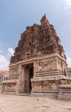 Hampi, Karnataka, Hindistan - 5 Kasım 2013: Vijaya Vitthala Tapınağı. Kırmızı taş gopuram bej taşın üstünde doğu kapısı mavi bulutların altında.