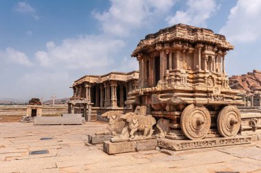 Hampi, Karnataka, Hindistan - 5 Kasım 2013: Vijaya Vitthala Tapınağı. Kahverengi taştan arabanın ön ve yan tarafında mavi bulutların altında.