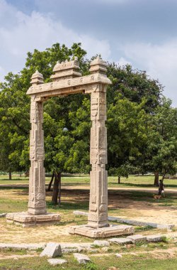 Hampi, Karnataka, Hindistan - 5 Kasım 2013: Antik Tapınak. Bej rengi taşın yakın plan portalı. Mavi bulutların altında yeşil yapraklar var..