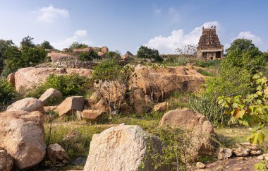 Hampi, Karnataka, Hindistan - 5 Kasım 2013: Malyavanta Raghunatha Tapınağı. Güney Gopuram kayaların, yeşil otların ve mavi bulutların altındaki ağaçların üzerinde görüldü..