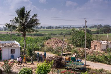 Lakkundi, Karnataka, Hindistan - 6 Kasım 2013: Brahma Jinalaya tapınağı. Önünde köy manzarası ve tarım manzarası var. İnsanlar, bisikletler, evler ve arabalar..