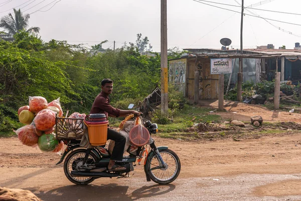 2013年11月7日 印度卡纳塔克邦南达凯什瓦尔 骑摩托车的流动小贩出售彩球 供儿童骑在绿叶和木制棚屋的泥土路上 — 图库照片