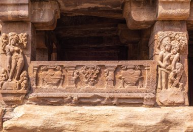 Aihole, Karnataka, Hindistan - 7 Kasım 2013: Chalukya Shiva Tapınağı. Kahverengi taşın girişindeki heykeller ve freskler birbirine aşık çiftleri ve diğer kadınları gösteriyor..