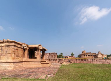 Aihole, Karnataka, Hindistan - 7 Kasım 2013: Kahverengi taş Lad Khan, Suryanarayana, ve açık mavi gökyüzü altında yeşil çimlerle Durga Gudi Tapınağı manzarası. 