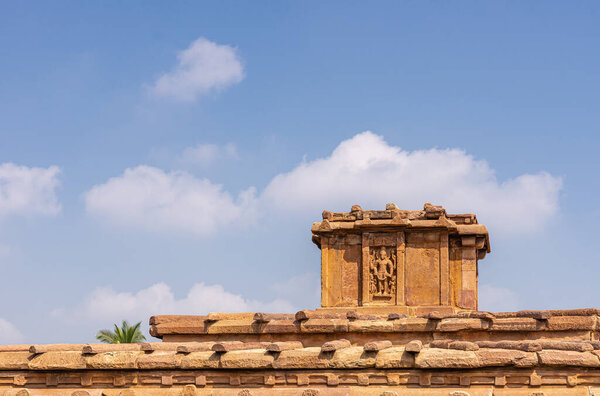 Aihole, Karnataka, India - November 7, 2013: Lad Khan or Chalukya Shiva Temple. Top statue of Shiva on brown stone building under blue cloudscape. 