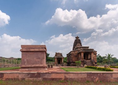 Aihole, Karnataka, Hindistan - 7 Kasım 2013: Huchchimalli Gudi veya Temple. Mavi bulutlar altında kahverengi taş binalar kompleksi. Arkadaki yeşil yapraklar..